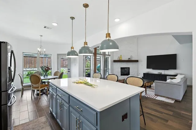 a open kitchen with stainless steel appliances kitchen island a table chairs in it and a flat screen tv