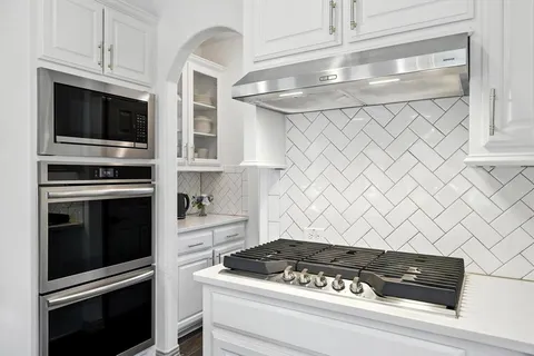 a kitchen with white cabinets and black appliances