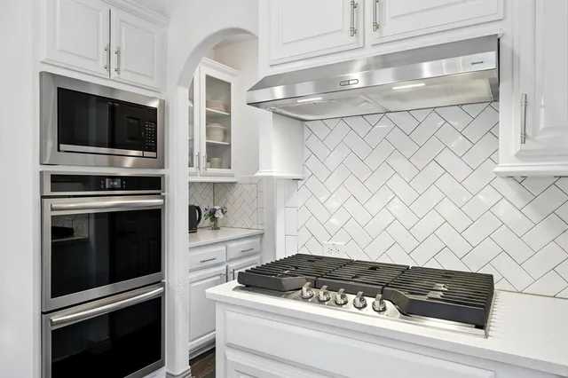 a kitchen with white cabinets and black appliances