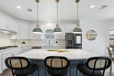 a kitchen with a table chairs a stove a microwave and a refrigerator