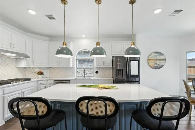 a kitchen with a table chairs a stove a microwave and a refrigerator