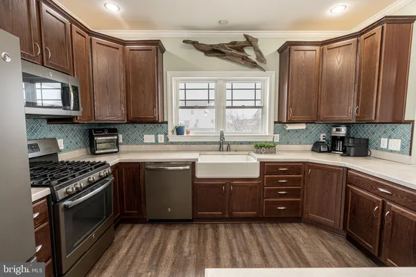 a kitchen with stainless steel appliances granite countertop a stove a sink dishwasher and cabinets with wooden floor