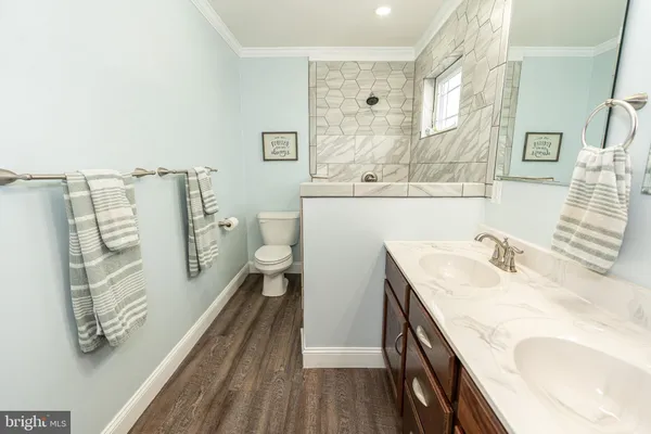 a bathroom with a granite countertop sink a toilet and shower