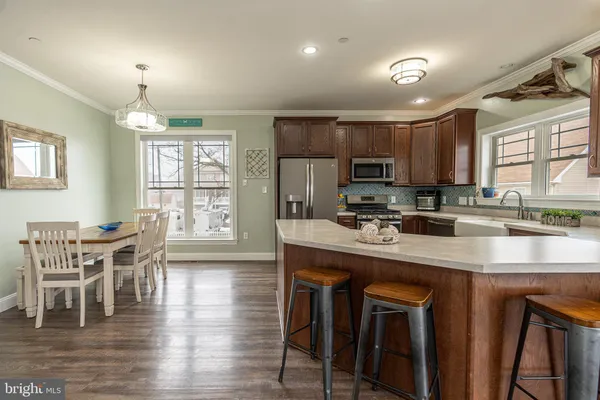 a kitchen with stainless steel appliances granite countertop a stove top oven a sink dishwasher a dining table and chairs with wooden floor