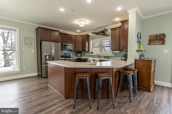 a kitchen with stainless steel appliances granite countertop a table chairs refrigerator and sink
