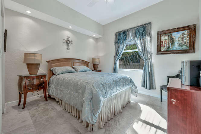 1640 Presidential Way, Unit 501 West Palm Beach, FL 33401 - Photo 22 of 36 a spacious bedroom with a bed and a flat screen tv