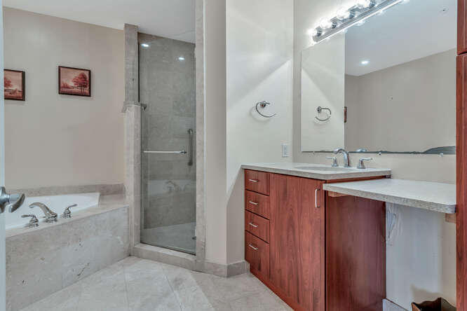 1640 Presidential Way, Unit 501 West Palm Beach, FL 33401 - Photo 26 of 36 a bathroom with a granite countertop sink mirror and a bathtub