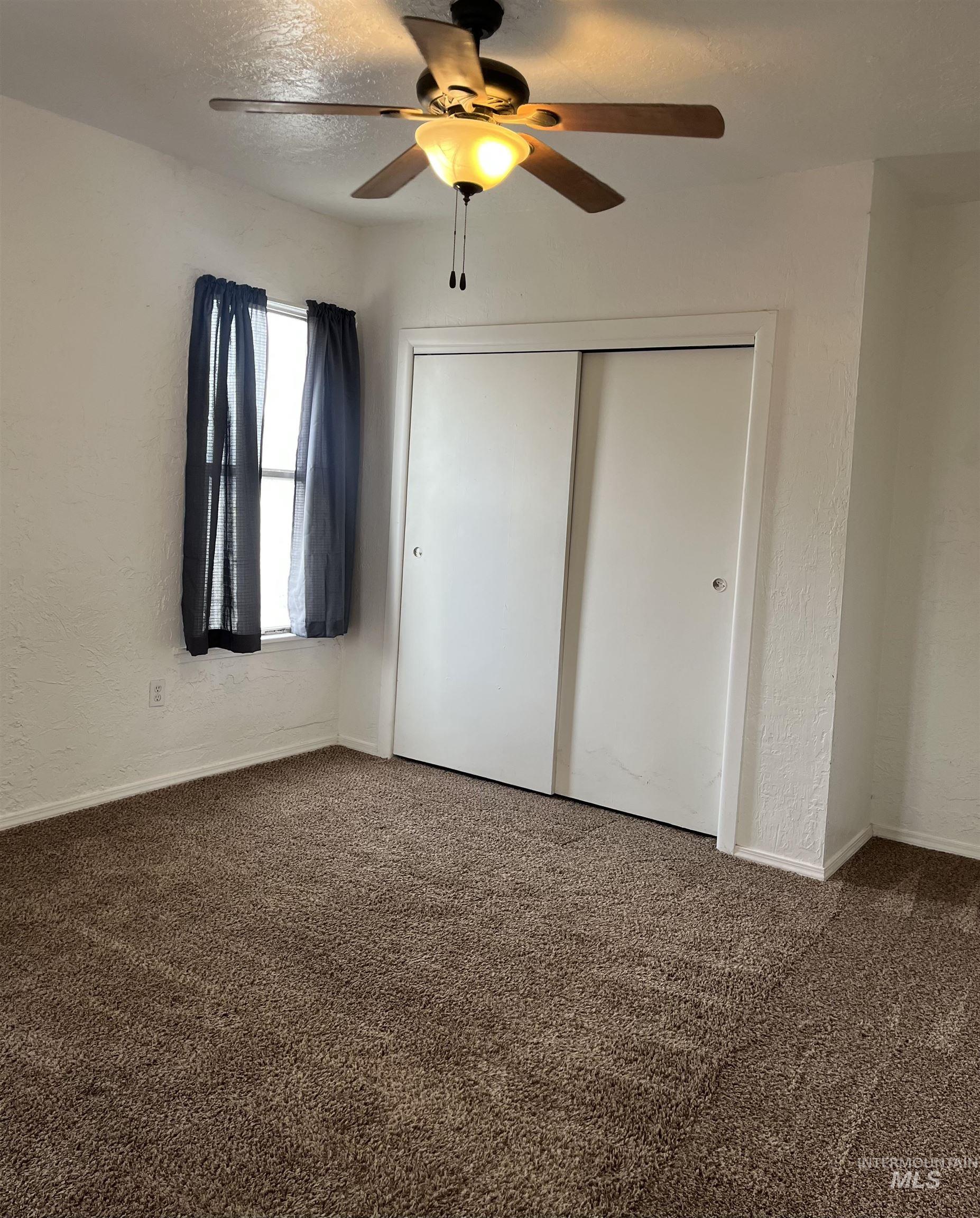 503 Stevens Avenue Filer, ID 83328 - Photo 5 of 13 Unfurnished bedroom with a textured wall, carpet floors, a ceiling fan, a textured ceiling, and a closet