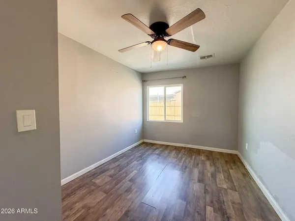 an empty room with wooden floor ceiling fan and windows