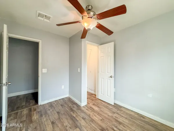an empty room with wooden floor fan and windows