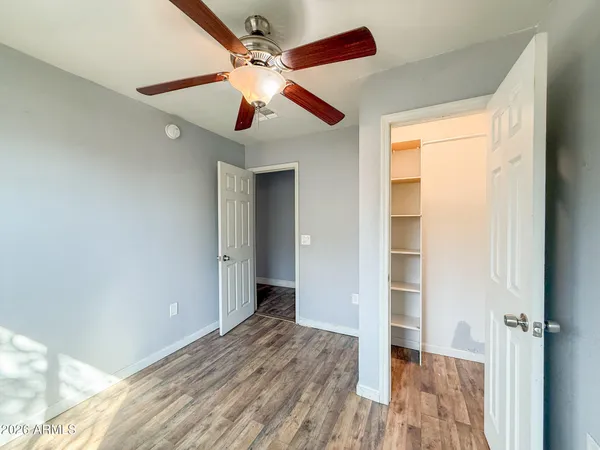 a view of a big room with wooden floor a ceiling fan and windows
