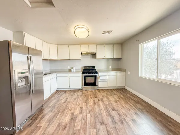 a kitchen with granite countertop a refrigerator oven a sink and cabinets