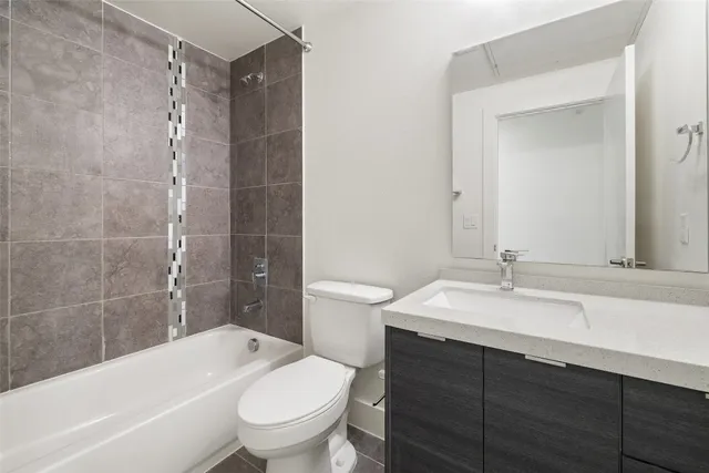 a bathroom with a granite countertop sink a toilet a mirror and bathtub