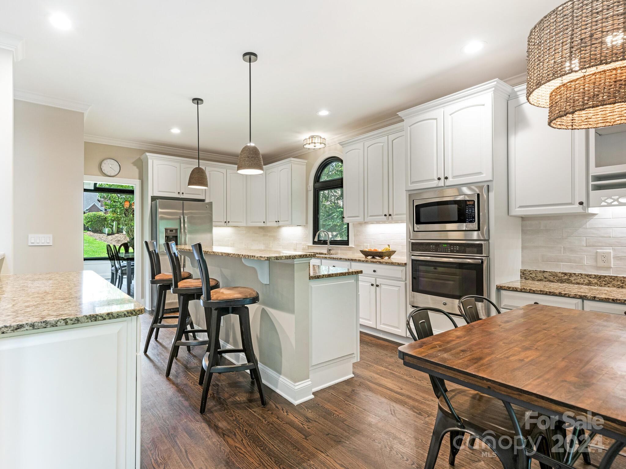 3234 Planters Ridge Road Charlotte, NC 28270 - Photo 10 of 33 a kitchen with stainless steel appliances granite countertop a stove a refrigerator a kitchen island a dining table and chairs with wooden floor