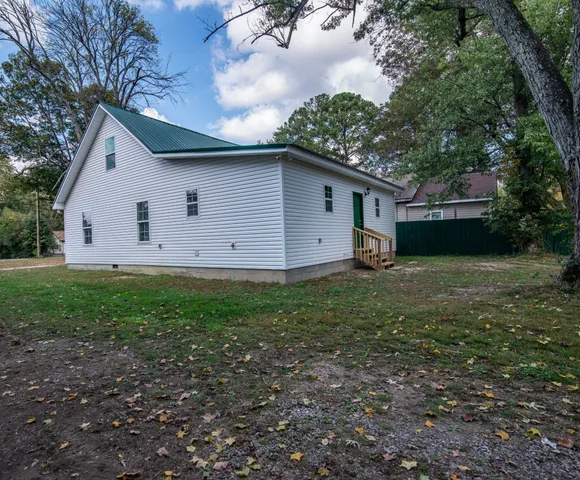 a backyard of a house with plants and large tree