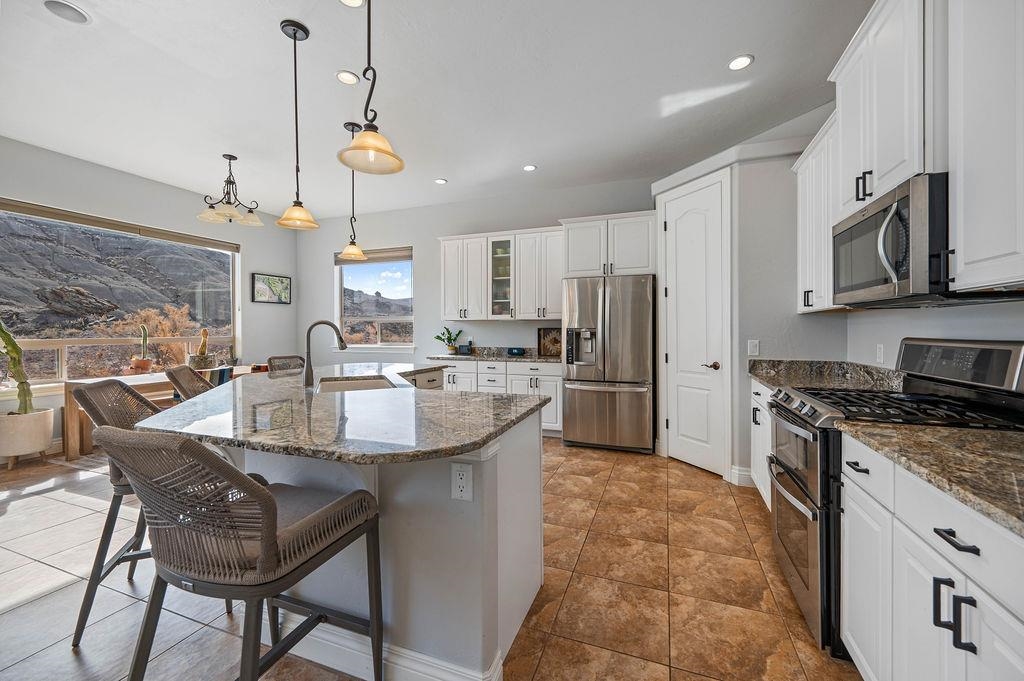 2283 Trail Ridge Road Grand Junction, CO 81507 - Photo 14 of 35 a kitchen with stainless steel appliances granite countertop a sink a stove a refrigerator cabinets and chairs