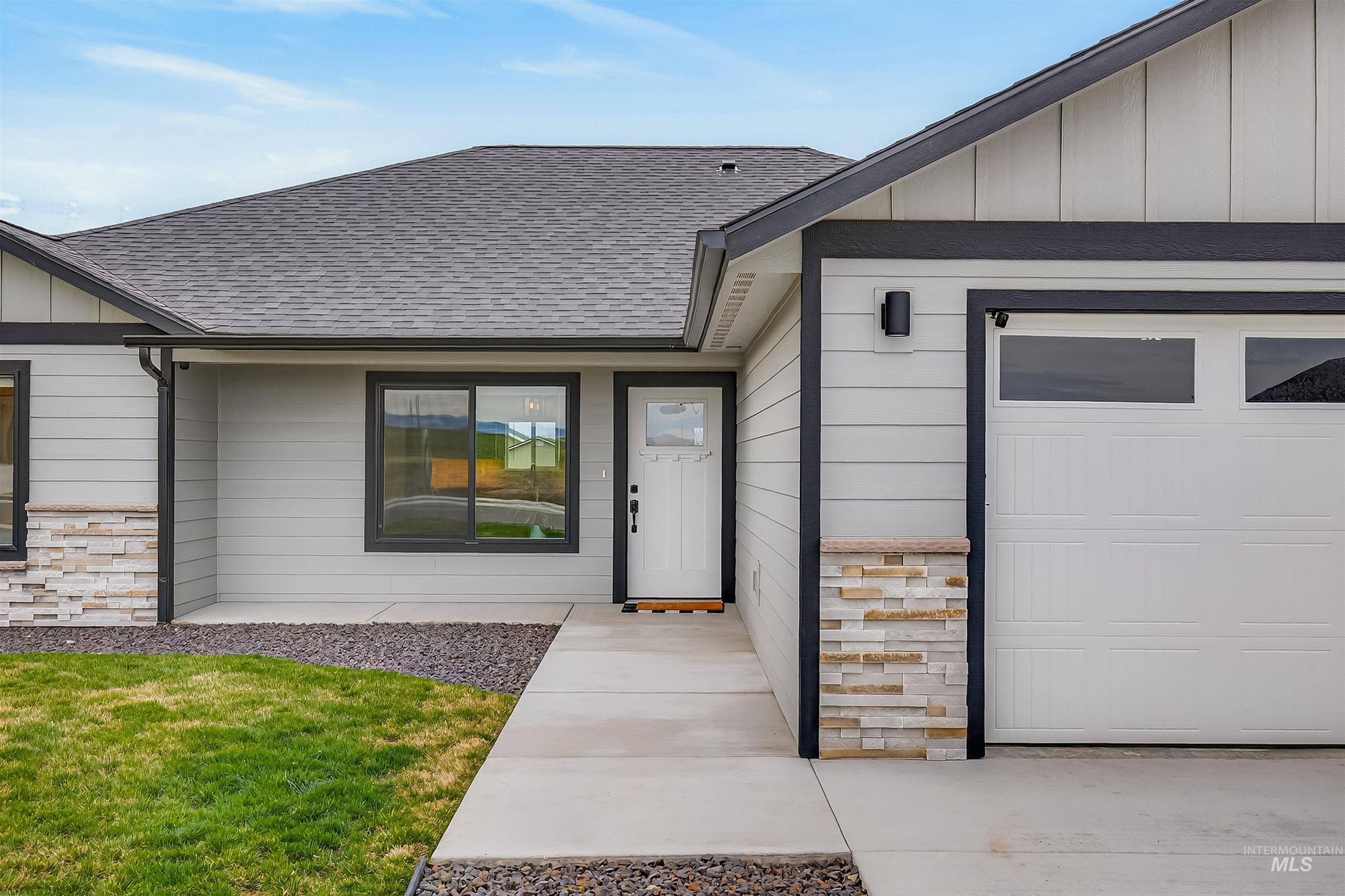 3732 Skyview Drive Lewiston, ID 83501 - Photo 3 of 47 Property entrance with stone siding, roof with shingles, a garage, board and batten siding, and a lawn
