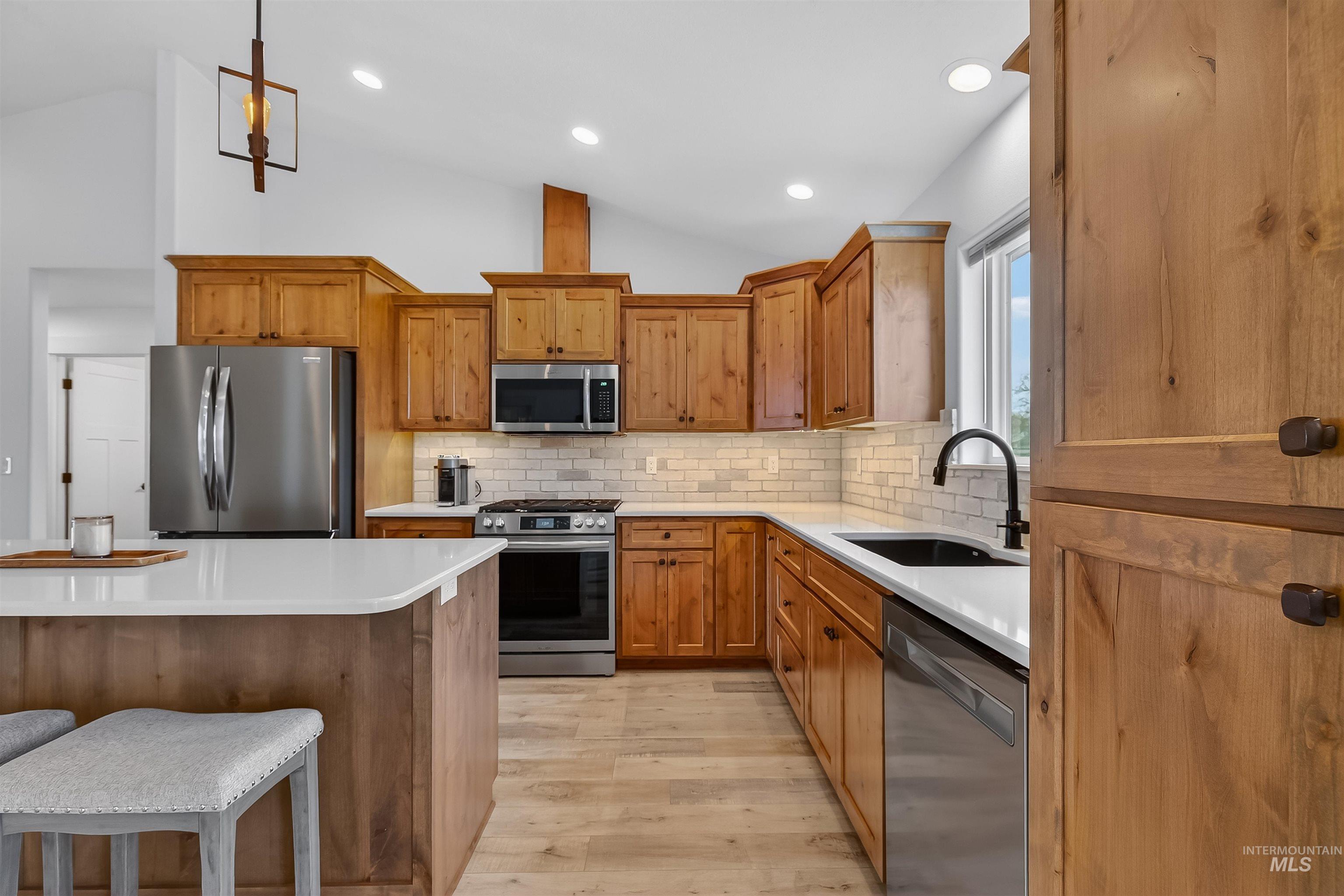 3732 Skyview Drive Lewiston, ID 83501 - Photo 8 of 47 Kitchen with a kitchen breakfast bar, wood finish cabinetry, stainless steel appliances, light wood finished floors, and vaulted ceiling