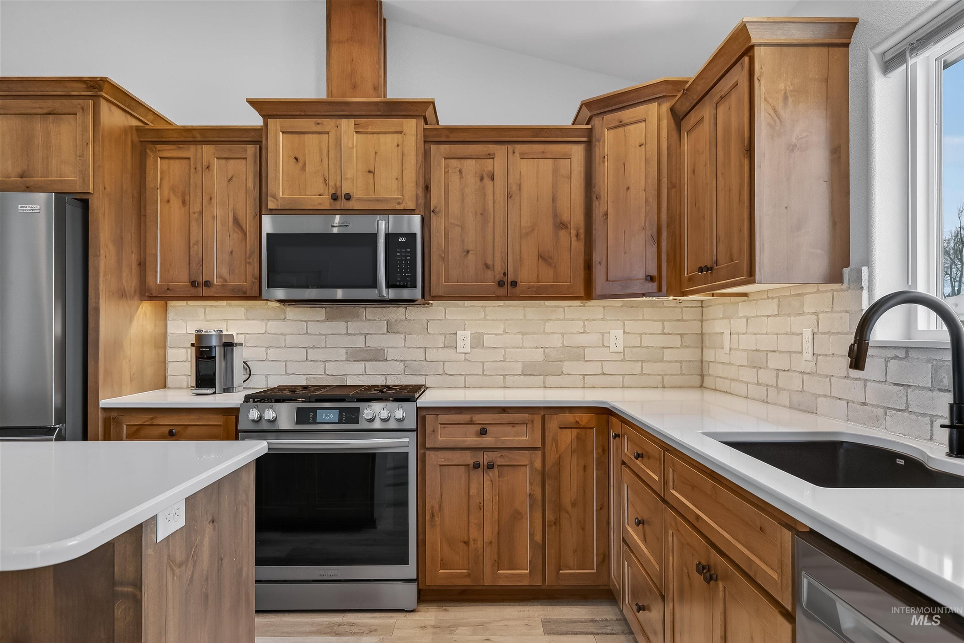 3732 Skyview Drive Lewiston, ID 83501 - Photo 10 of 47 Kitchen with stainless steel appliances, wood finish cabinetry, decorative backsplash, lofted ceiling, and light wood-type flooring