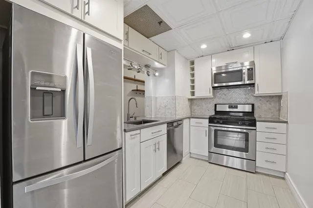 a kitchen with stainless steel appliances granite countertop a stove a refrigerator and a microwave