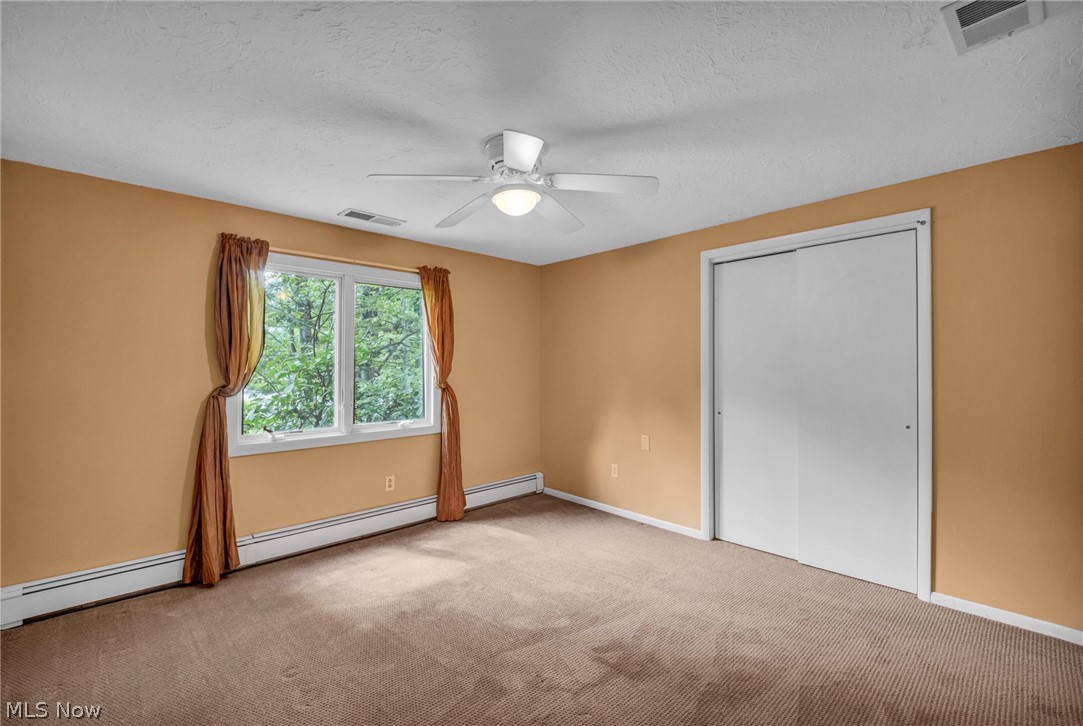 6845 Liberty Road Solon, OH 44139 - Photo 29 of 47 Carpeted interior space featuring a large window, ceiling fan with integrated lighting, built-in closet with sliding doors, and baseboard heating