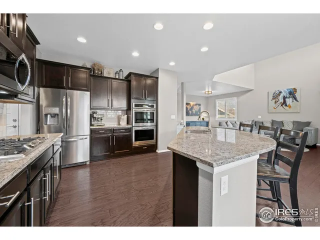 a kitchen with stainless steel appliances kitchen island granite countertop a table chairs stove and refrigerator