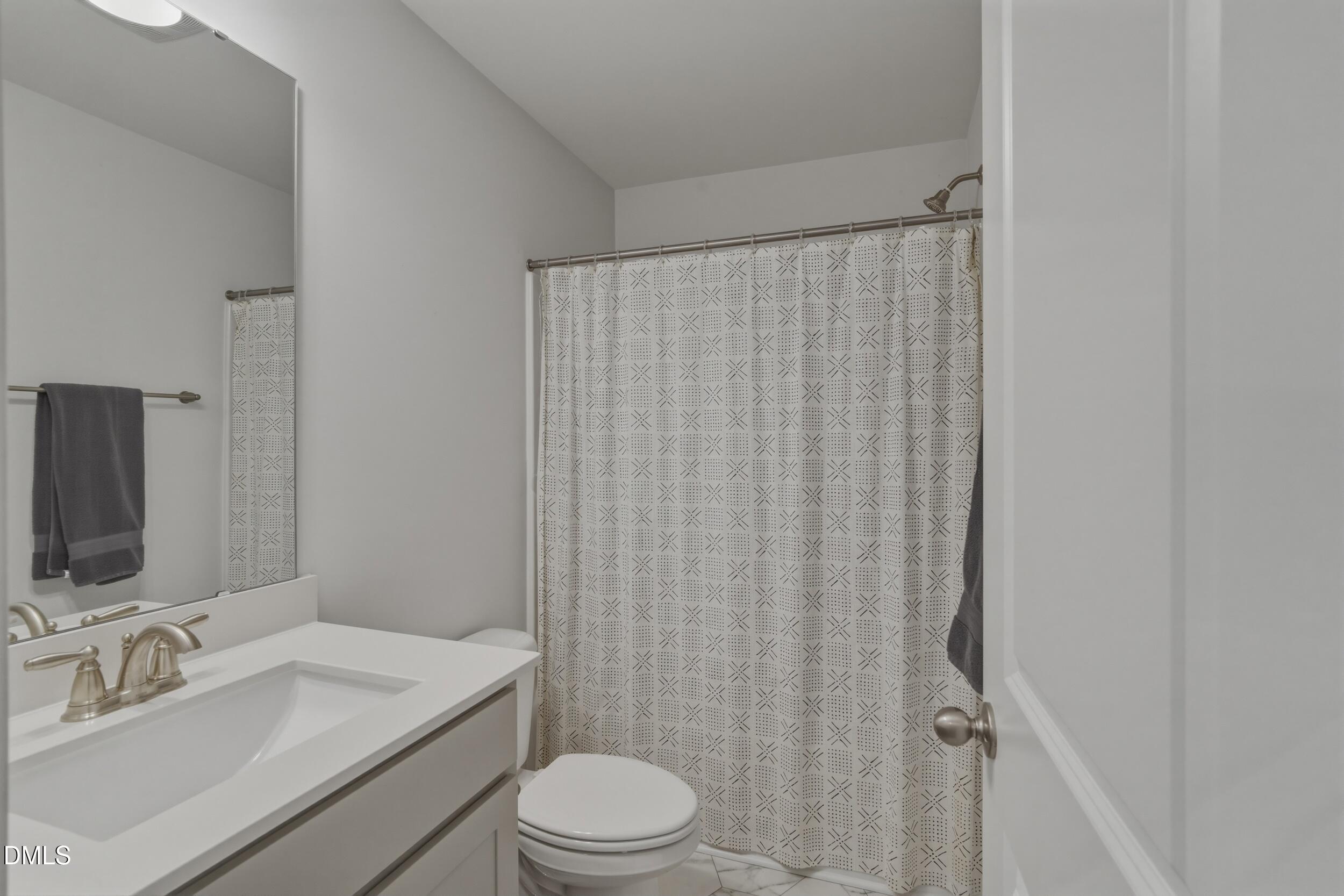 386 Howards Crossing Drive Wendell, NC 27591 - Photo 20 of 31 a bathroom with a sink a toilet a mirror and shower curtain