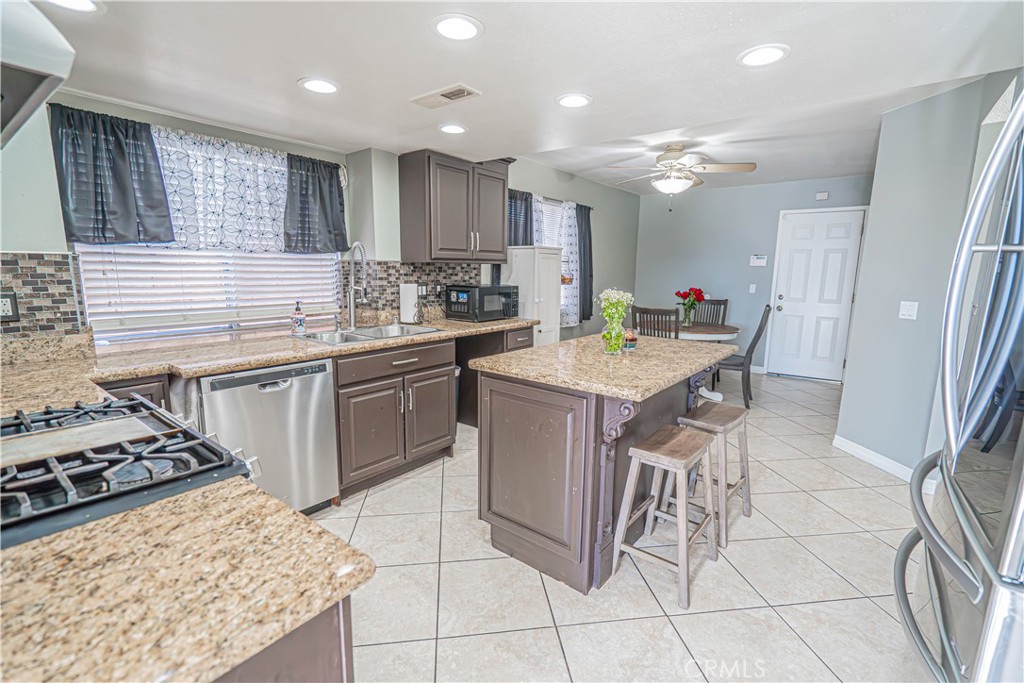 28076 Wildwind Road Canyon Country, CA 91351 - Photo 11 of 48 a kitchen with a sink a stove a refrigerator and chairs