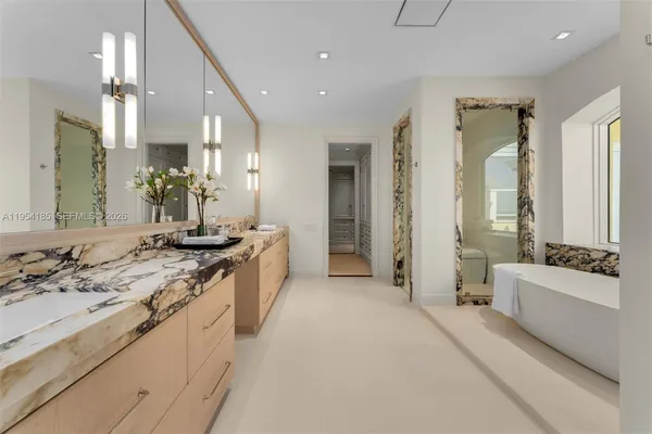 a large bathroom with a double vanity sink a large mirror and a bathtub