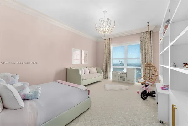 a bedroom with a bed a chandelier and a large mirror on the dresser