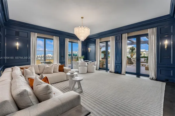 a living room with furniture large windows and a chandelier
