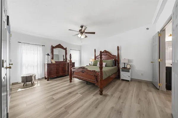 a spacious bedroom with a bed a chandelier and a dresser