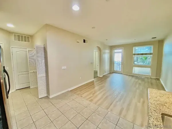 a view of an empty room with window and wooden floor