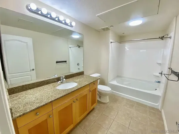 a spacious bathroom with a granite countertop sink a toilet a mirror and bathtub