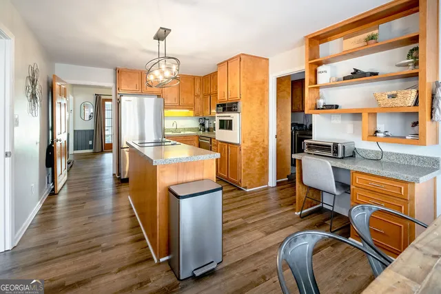 a kitchen with stainless steel appliances granite countertop a stove top oven a refrigerator a dining table and chairs with wooden floor