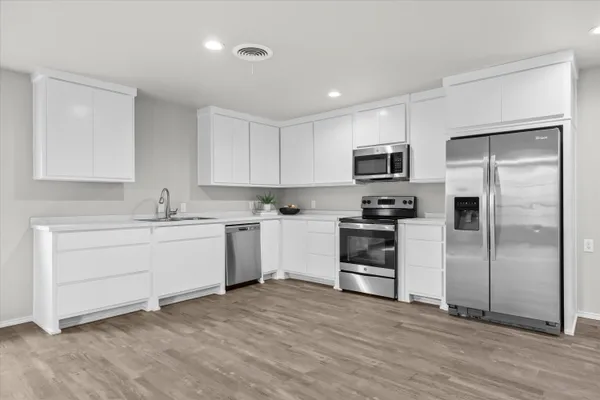 a kitchen with a refrigerator stove and white cabinets