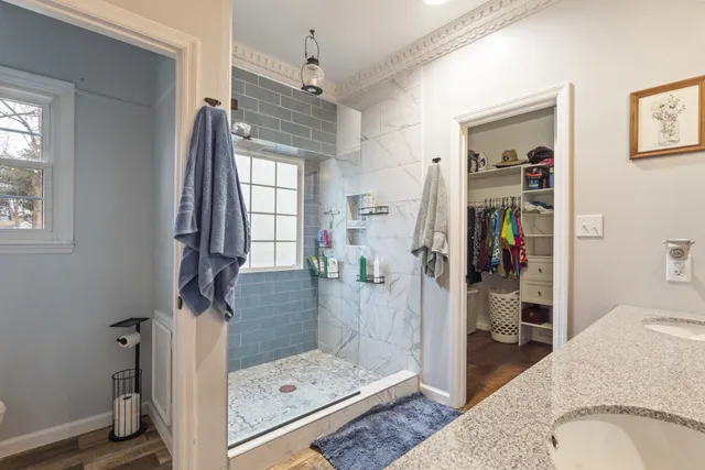 a bathroom with a granite countertop sink a mirror and shower