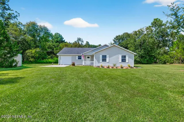 a yellow and white house with a yard and wooden fence