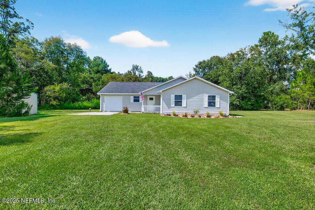 a yellow and white house with a yard and wooden fence