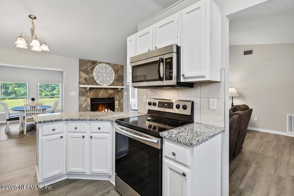 17080 Mcintosh Road Hilliard, FL 32046 - Photo 16 of 52 a kitchen with stainless steel appliances granite countertop a stove top oven a sink dishwasher and a microwave oven with white cabinets