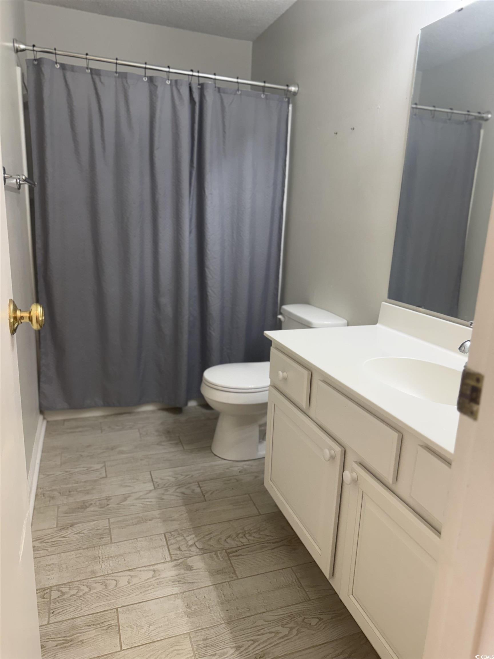 1850 Colony Drive, Unit 2S Myrtle Beach, SC 29575 - Photo 11 of 38 Full bathroom with vanity, a shower with curtain, wood tiled floors, and a textured ceiling