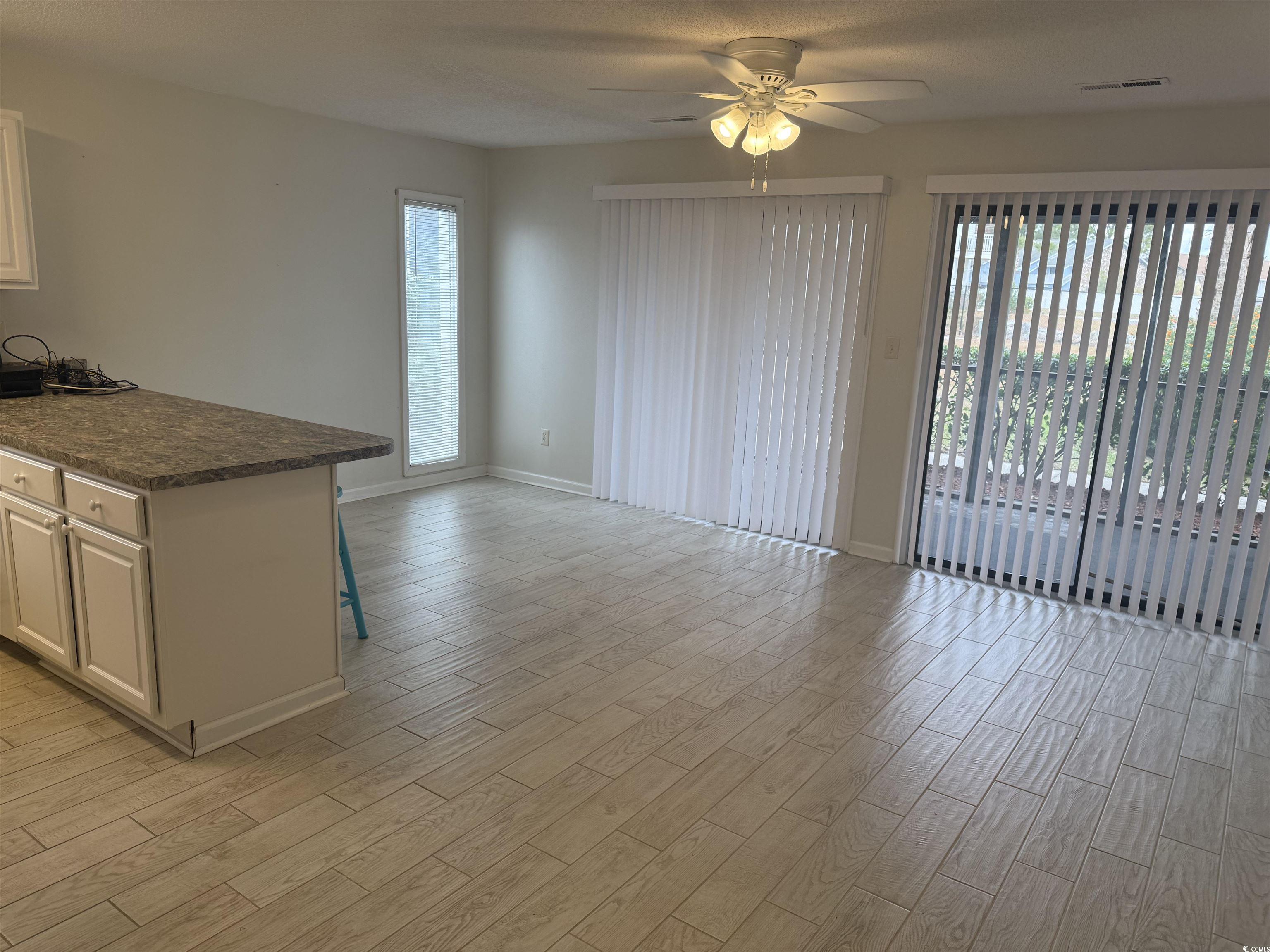 1850 Colony Drive, Unit 2S Myrtle Beach, SC 29575 - Photo 6 of 38 Unfurnished living room featuring wood tiled floors, ceiling fan, healthy amount of natural light, and a textured ceiling