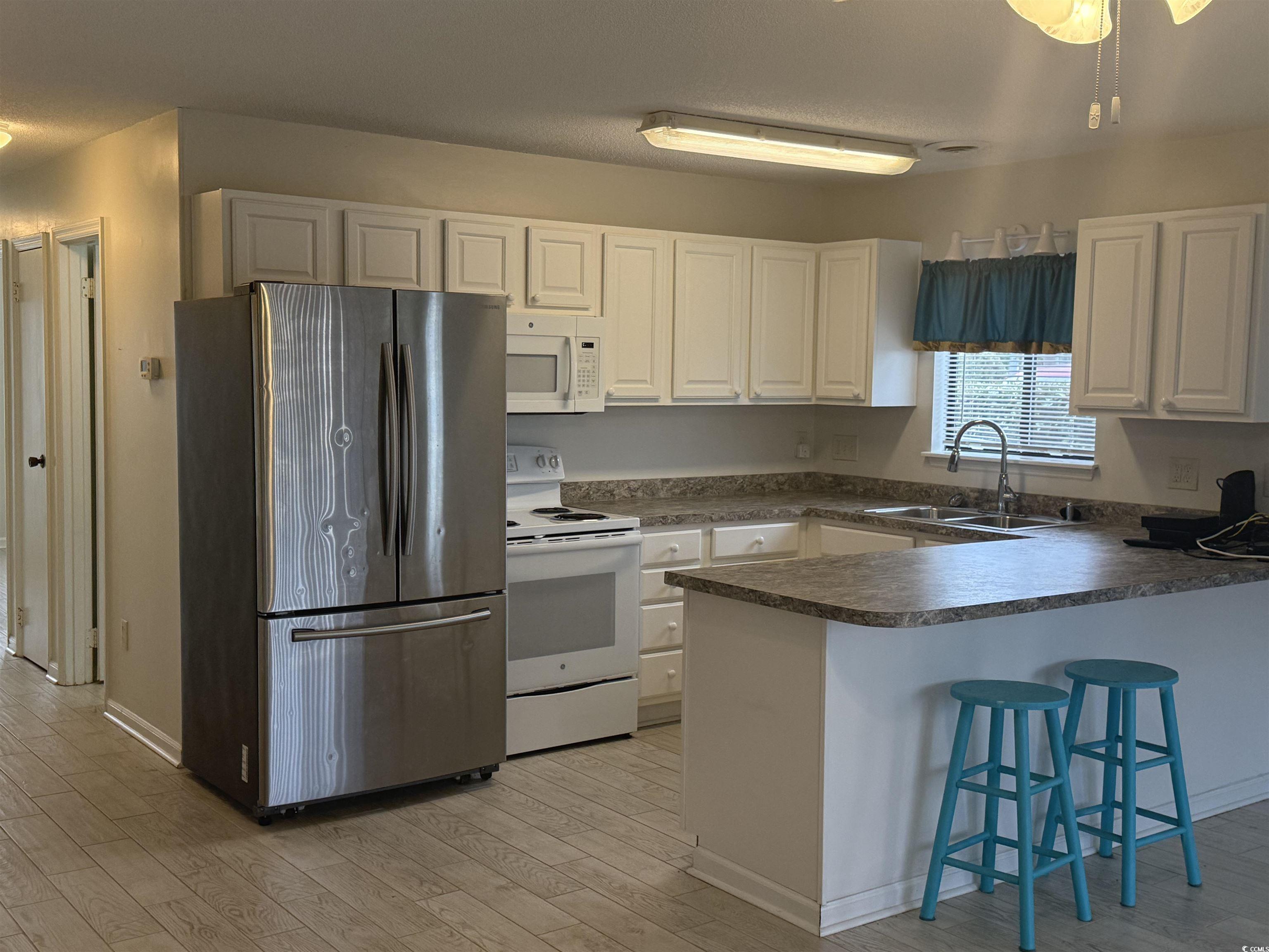 1850 Colony Drive, Unit 2S Myrtle Beach, SC 29575 - Photo 7 of 38 Kitchen with white appliances, dark countertops, a breakfast bar, white cabinets, and a peninsula