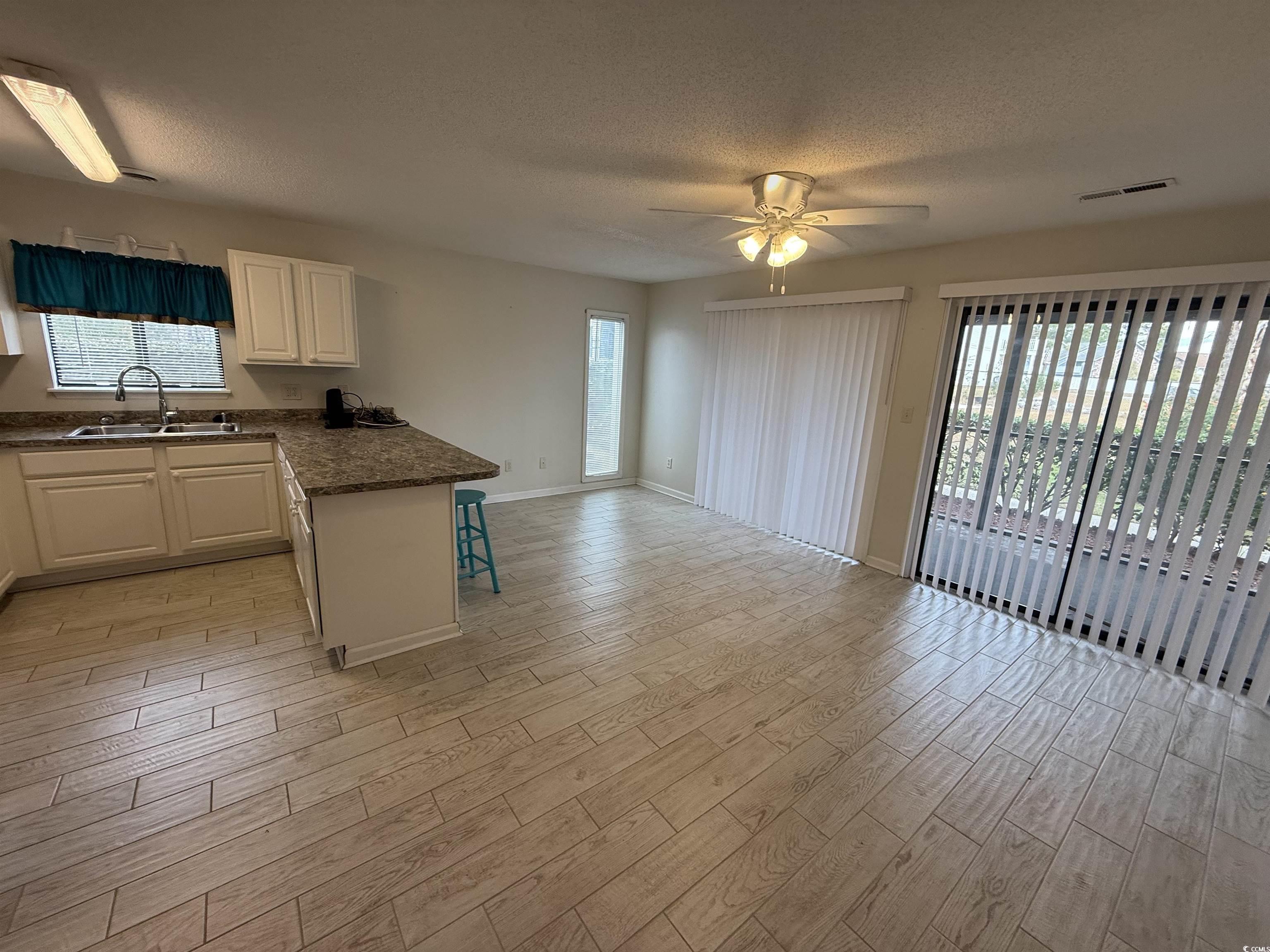 1850 Colony Drive, Unit 2S Myrtle Beach, SC 29575 - Photo 9 of 38 Kitchen with a kitchen bar, wood tiled floors, a textured ceiling, a peninsula, and a ceiling fan