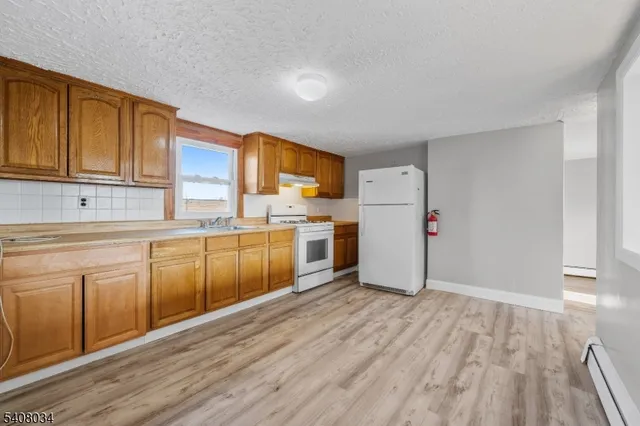 a kitchen with white cabinets and wooden floor