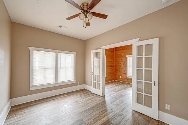 an empty room with wooden floor and windows