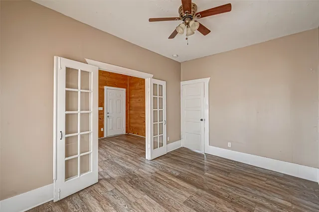 a view of an empty room with wooden floor and a window