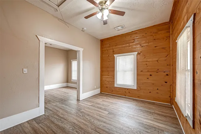 a view of an empty room with wooden floor and a window