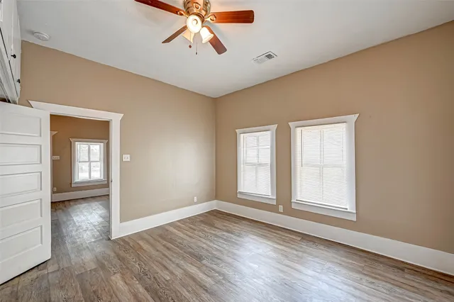 a view of empty room with wooden floor and fan