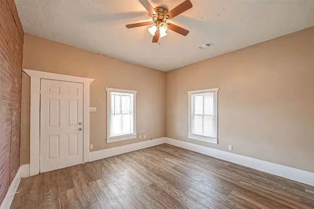 a view of empty room with wooden floor and fan